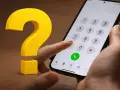 Hur gör man för att flytta simkort till ny mobil? En stor gul fråga och en hand som håller en telefon med knappsatsen framme.