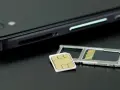 En mobiltelefon och ett SIM-kort bredvid SIM-kortshållaren. Kanske dags att byta SIM-kort för att kunna ringa utan simkort?