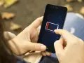 En person håller en mobil med lågt batteri. Det är mörkt ute, som om mobilen drar batteri på natten.