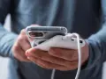 En person laddar sin mobiltelefon med en powerbank. Frågan "vad kostar det att ladda en mobiltelefon" är relevant när man använder en extern laddare.