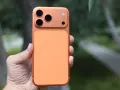 En hand håller en orange iPhone 16 Pro Max med tre kameror.