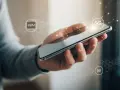 En hand håller en smartphone med ikoner för eSIM och 5G. Enkel process att flytta eSIM till ny telefon.