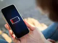 En person håller en mobil med lågt batteri. Kanske 5G drar mer batteri än väntat.