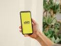 En hand håller en telefon med en gul skärm som visar "eSIM". Dags att byta SIMkort till ett eSIM för en smidigare upplevelse.