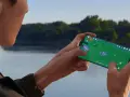 Person spelar mobilspel vid vattnet. Telefonen blir varm och drar batteri, men spelet är fängslande.