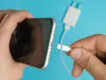 En hand håller en iPhone och en laddkabel. Var försiktig med vatten i ladduttaget på din iPhone.