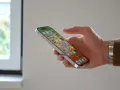 En hand håller en iPhone 12 med många appar. Bra iphone 12 batteritid gör att du kan använda den hela dagen.