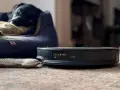 En robotdammsugare med lidar scanner nära en hunds bädd.