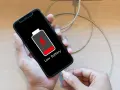 En person laddar sin mobiltelefon med lågt batteri. Viktigt att spara bilder från mobilen innan batteriet tar slut!