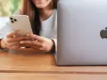 Person använder en iPhone för att skicka bilder från Samsung till iPhone. En MacBook ligger bredvid.