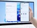 En hand håller en Samsung-telefon framför en laptop. Laptopen visar ett fönster för filöverföring, vilket underlättar att byta från iPhone till Samsung.