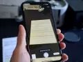 En hand håller en iPhone för att scanna ett dokument. Skärmen visar en förhandsgranskning av det skannade dokumentet och alternativ för att avbryta eller spara.