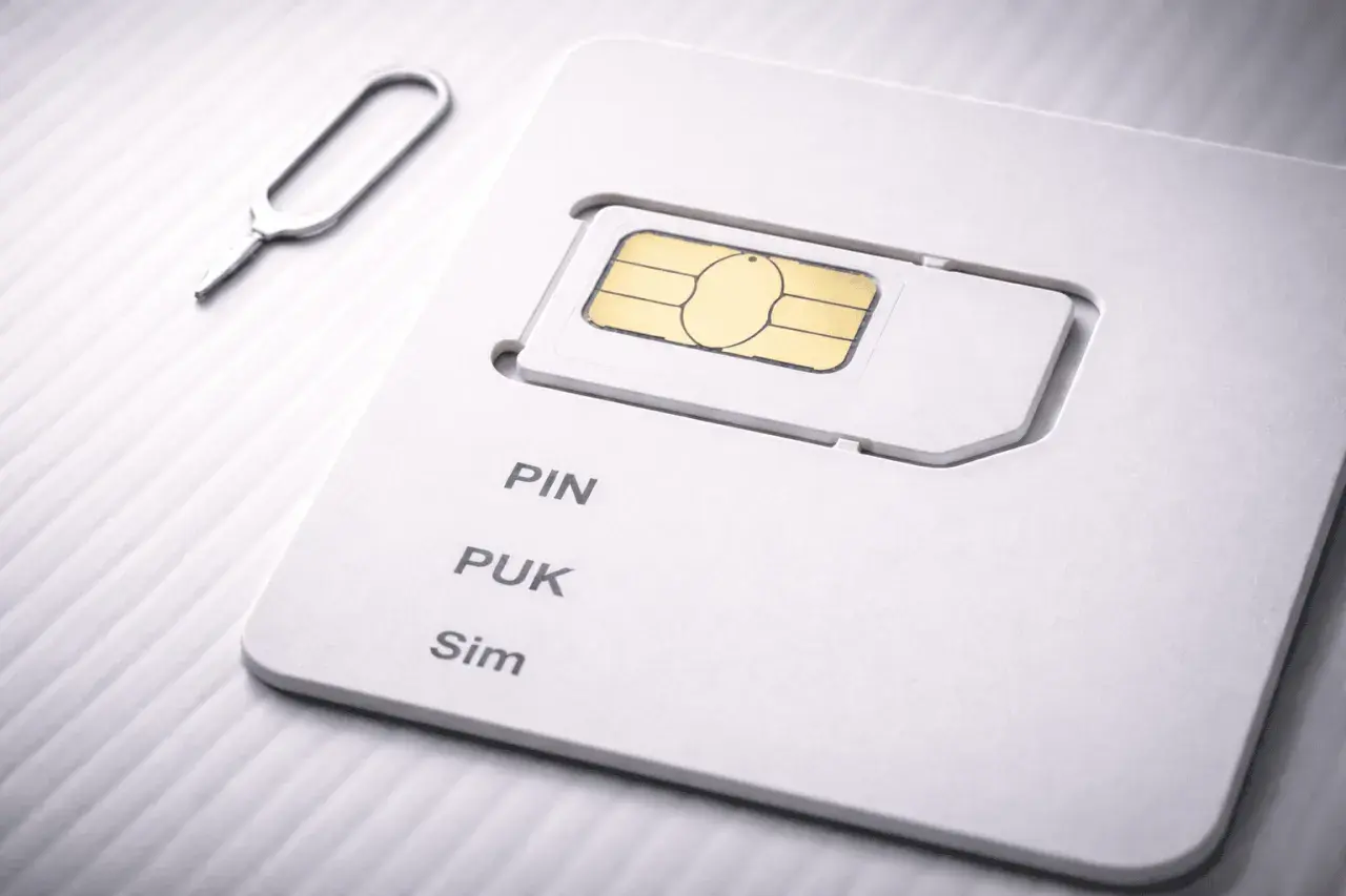 SIM-kort med PIN- och PUK-kod. Ett verktyg för att ta ut SIM-kortet ligger bredvid.