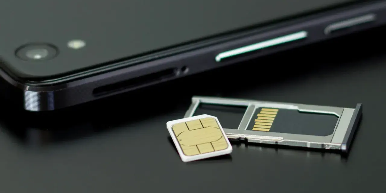 En mobiltelefon och ett SIM-kort bredvid SIM-kortshållaren. Kanske dags att byta SIM-kort för att kunna ringa utan simkort?