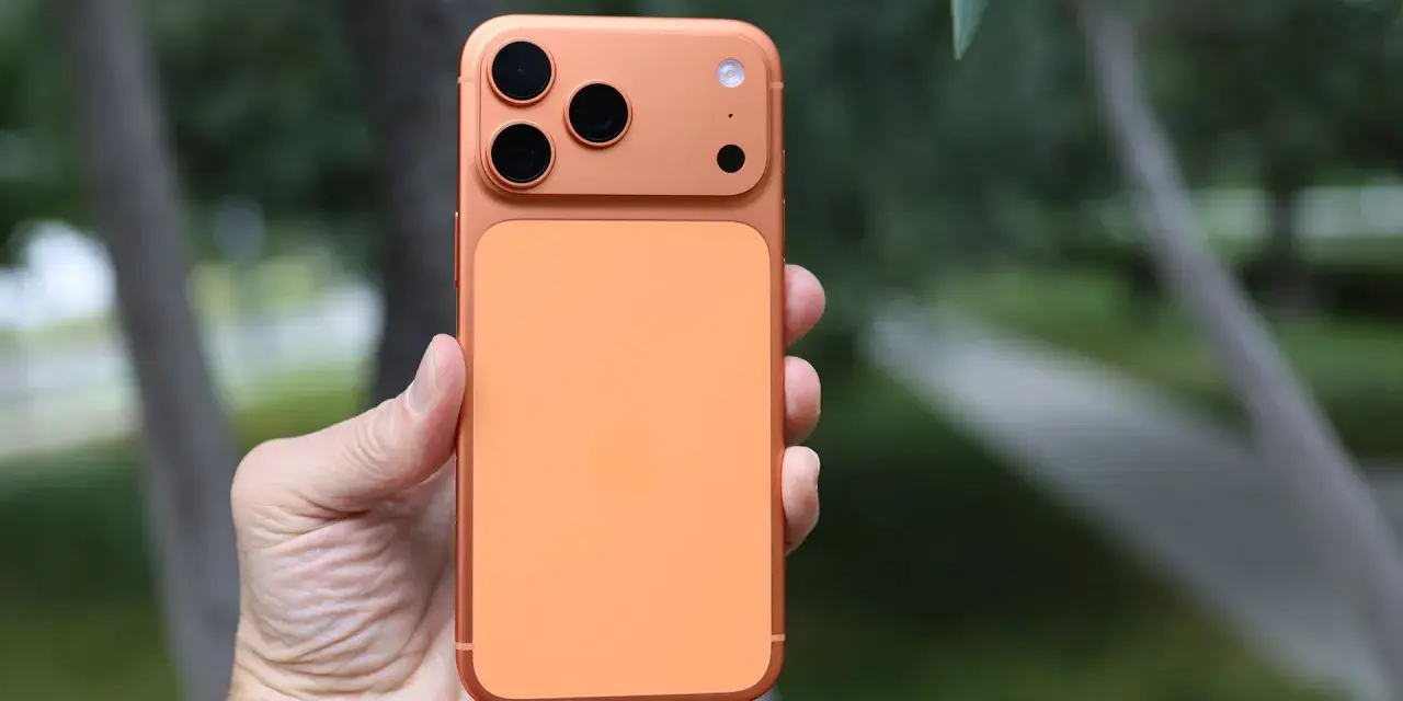 En hand håller en orange iPhone 16 Pro Max med tre kameror.