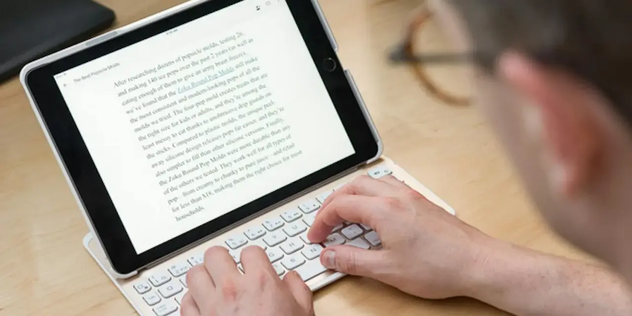 Person skriver på ett iPad-tangentbord. En text om "Zoku Round Pop Molds" visas på skärmen, vilket tyder på ett iPad-tangentbordstest.