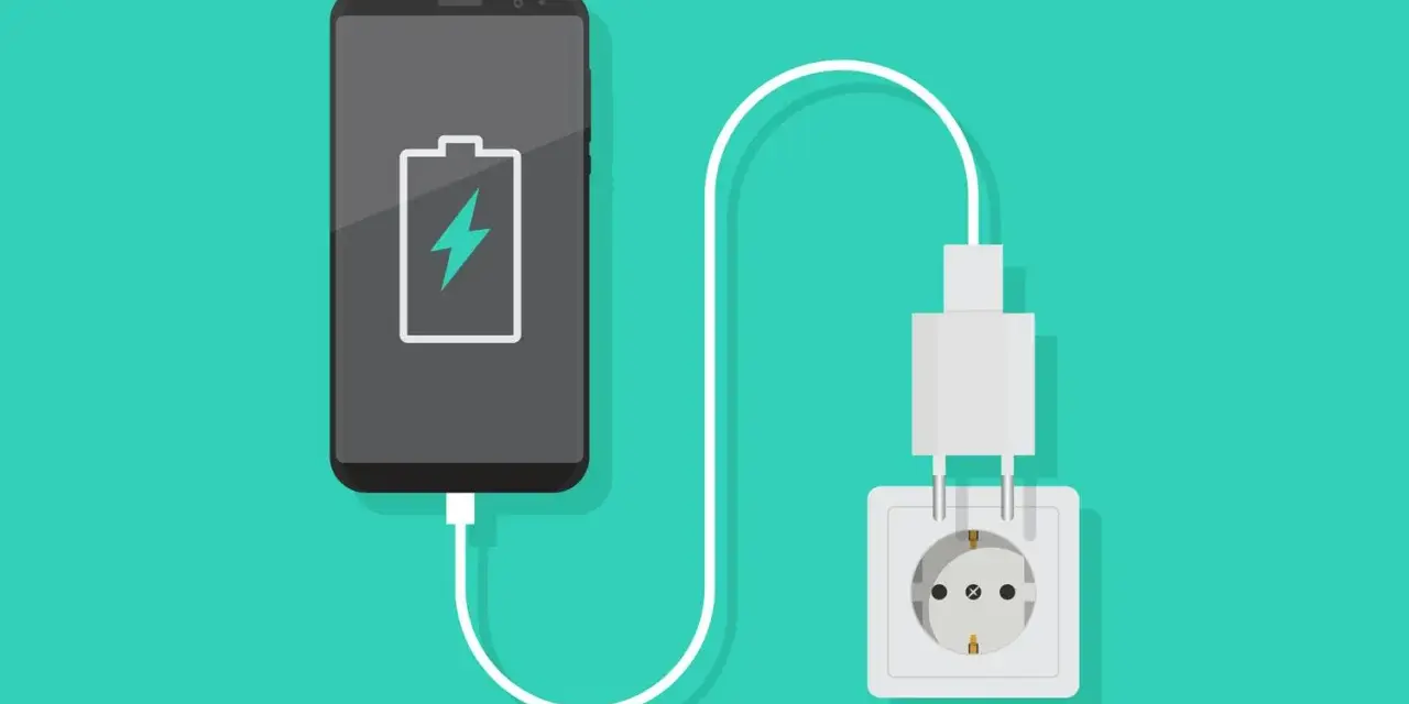 En smartphone med lågt batteri laddas via ett vägguttag.