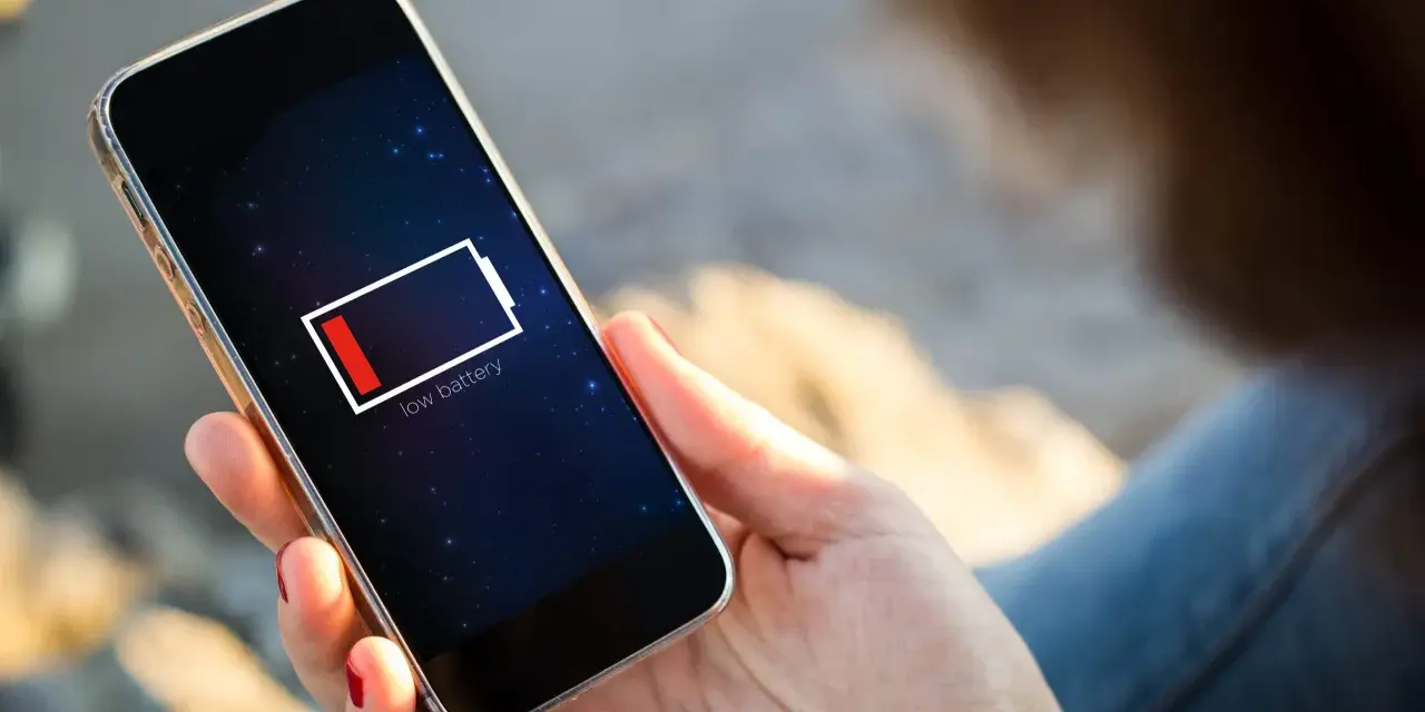 En person håller en mobil med lågt batteri. Kanske 5G drar mer batteri än väntat.