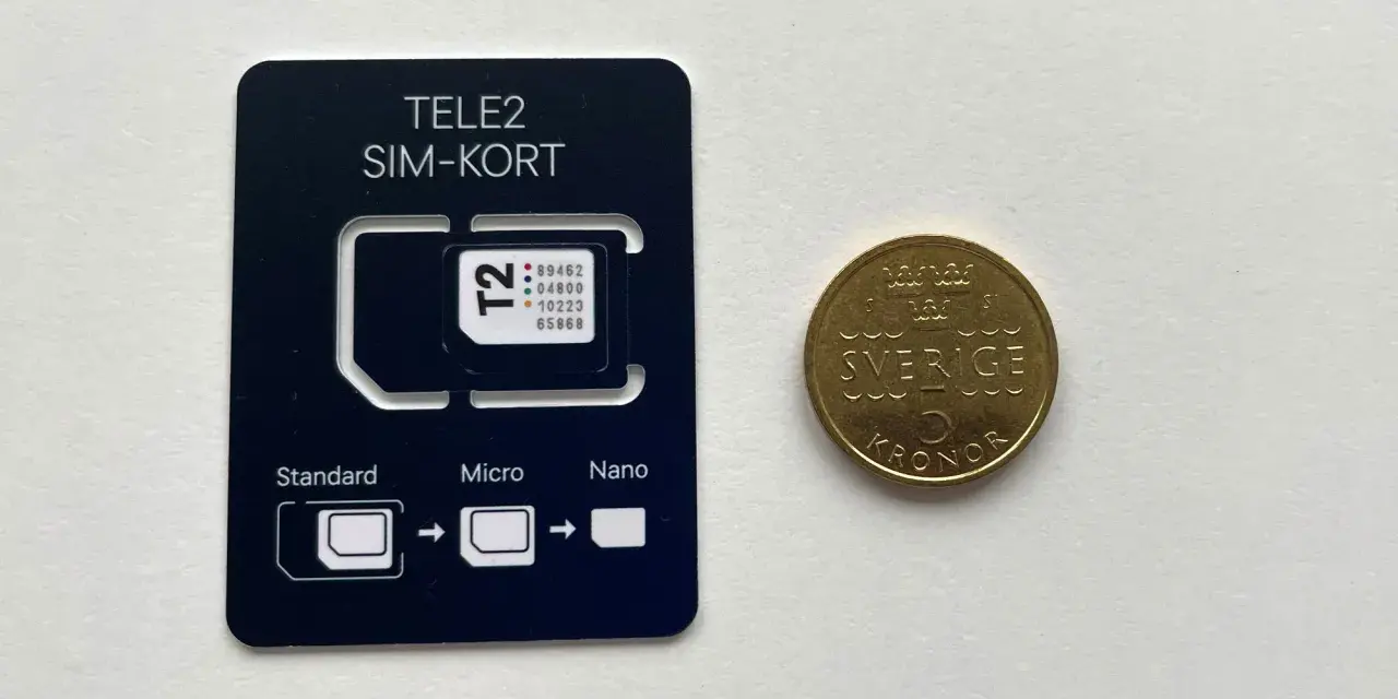 Ett Tele2 SIM-kort med utbrytbara delar för olika storlekar. Bredvid ligger en femkronorsmynt. Frågan om man kan ha två simkort med samma nummer är relevant för att hantera flera enheter.