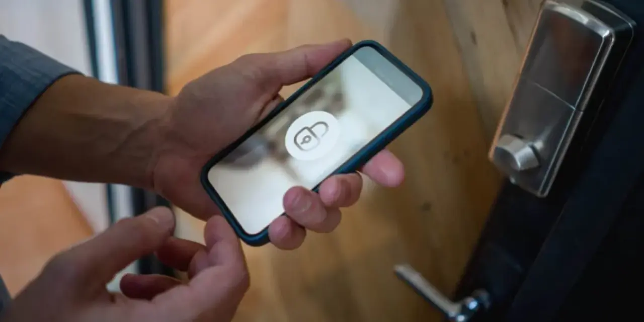 En person håller en iPhone 6 med en upplåsningsikon på skärmen, redo att låsa upp dörren.