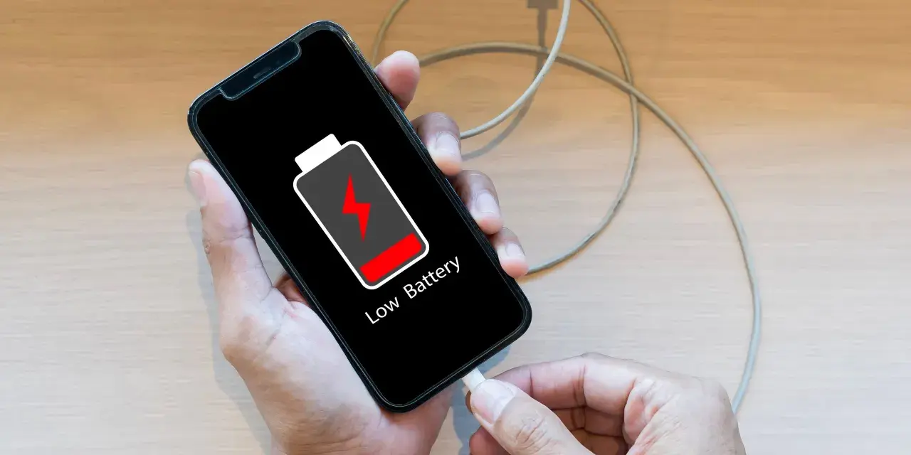 En person laddar sin mobiltelefon med lågt batteri. Viktigt att spara bilder från mobilen innan batteriet tar slut!