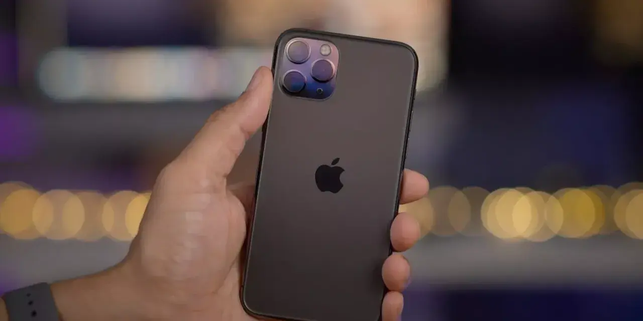 En hand håller en mörk iPhone 11 Pro med sin imponerande trippelkamera.