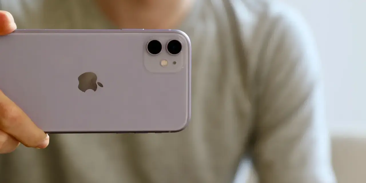 En person håller upp en lila iPhone 11. Man ser tydligt den dubbla iphone 11 kameran på baksidan.