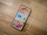 Samsung-telefon med stylus och simkort. En skärm visar "Good afternoon" och väder.