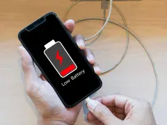 En person laddar sin mobiltelefon med lågt batteri. Viktigt att spara bilder från mobilen innan batteriet tar slut!