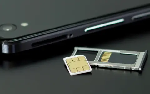 En mobiltelefon och ett SIM-kort bredvid SIM-kortshållaren. Kanske dags att byta SIM-kort för att kunna ringa utan simkort?