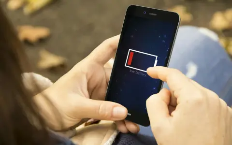 En person håller en mobil med lågt batteri. Det är mörkt ute, som om mobilen drar batteri på natten.