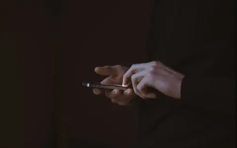 Händer som snabbtstartar en iPhone i mörkret.