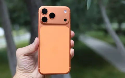 En hand håller en orange iPhone 16 Pro Max med tre kameror.