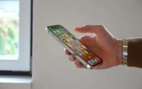 En hand håller en iPhone 12 med många appar. Bra iphone 12 batteritid gör att du kan använda den hela dagen.