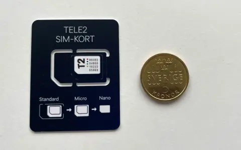 Ett Tele2 SIM-kort med utbrytbara delar för olika storlekar. Bredvid ligger en femkronorsmynt. Frågan om man kan ha två simkort med samma nummer är relevant för att hantera flera enheter.