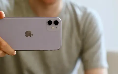 En person håller upp en lila iPhone 11. Man ser tydligt den dubbla iphone 11 kameran på baksidan.