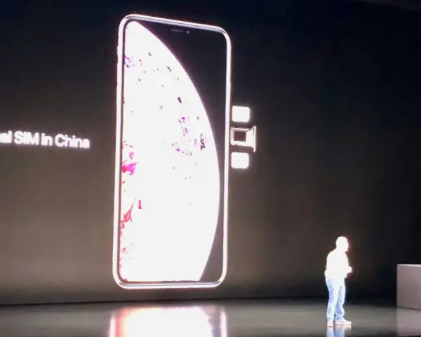 En stor bild av en iPhone visas på en skärm, med texten "Dual SIM in China". Bredvid telefonen syns två små SIM-kort.