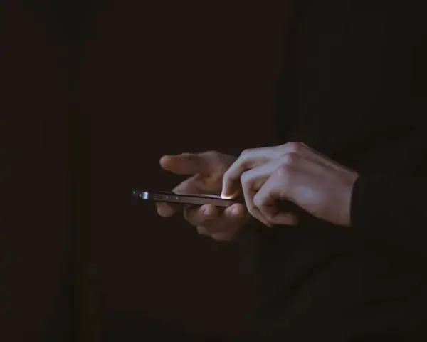 Händer som snabbtstartar en iPhone i mörkret.