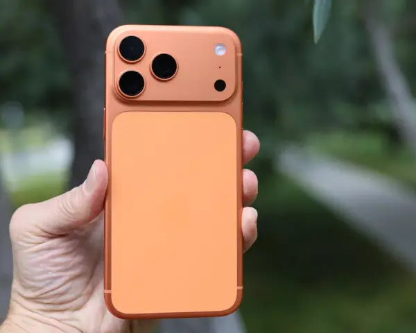 En hand håller en orange iPhone 16 Pro Max med tre kameror.