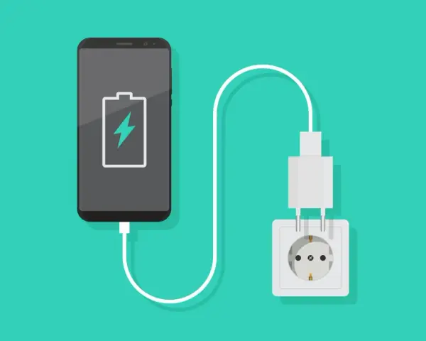 En smartphone med lågt batteri laddas via ett vägguttag.