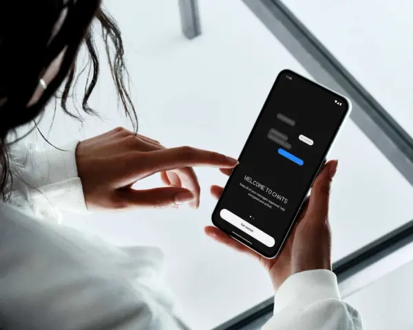 En person håller en smartphone som visar en chattapp. Enkel design för att skapa sms grupp iphone och android.
