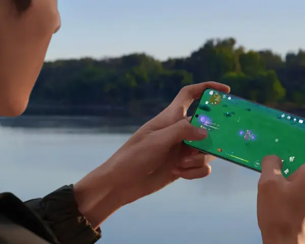 Person spelar mobilspel vid vattnet. Telefonen blir varm och drar batteri, men spelet är fängslande.