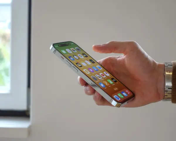 En hand håller en iPhone 12 med många appar. Bra iphone 12 batteritid gör att du kan använda den hela dagen.