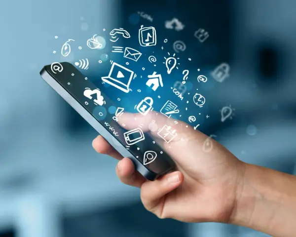 En hand håller en smartphone med ikoner som flyger ut, som symboliserar gratis appar för Android.