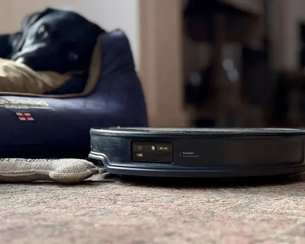 En robotdammsugare med lidar scanner nära en hunds bädd.