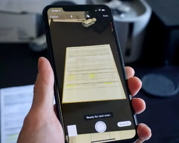En hand håller en iPhone för att scanna ett dokument. Skärmen visar en förhandsgranskning av det skannade dokumentet och alternativ för att avbryta eller spara.