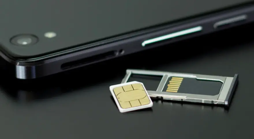 En mobiltelefon och ett SIM-kort bredvid SIM-kortshållaren. Kanske dags att byta SIM-kort för att kunna ringa utan simkort?