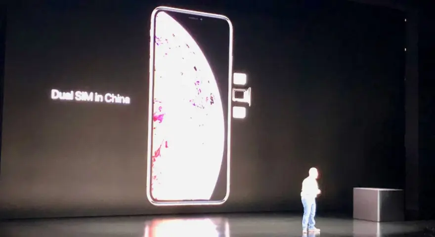 En stor bild av en iPhone visas på en skärm, med texten "Dual SIM in China". Bredvid telefonen syns två små SIM-kort.