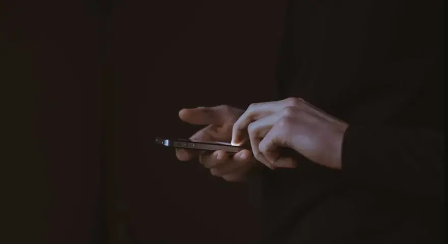Händer som snabbtstartar en iPhone i mörkret.