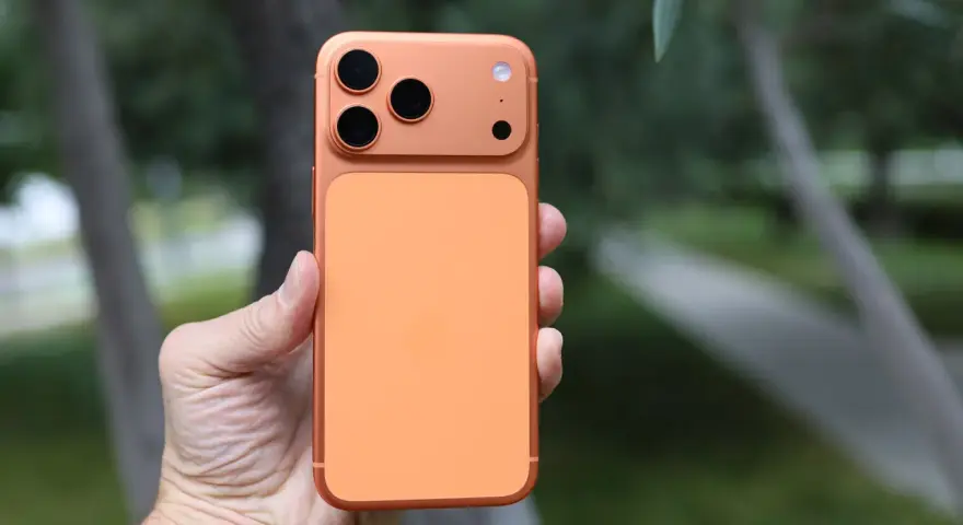 En hand håller en orange iPhone 16 Pro Max med tre kameror.